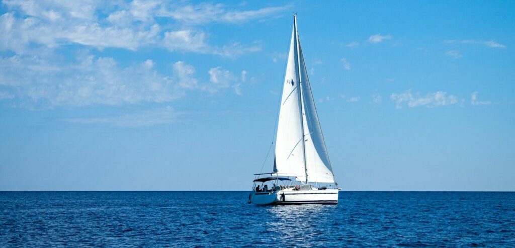 white sailboat on sea under blue sky during daytime