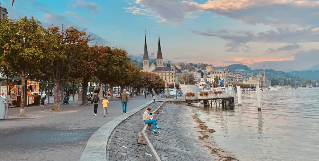 people walking on sidewalk near body of water during daytime