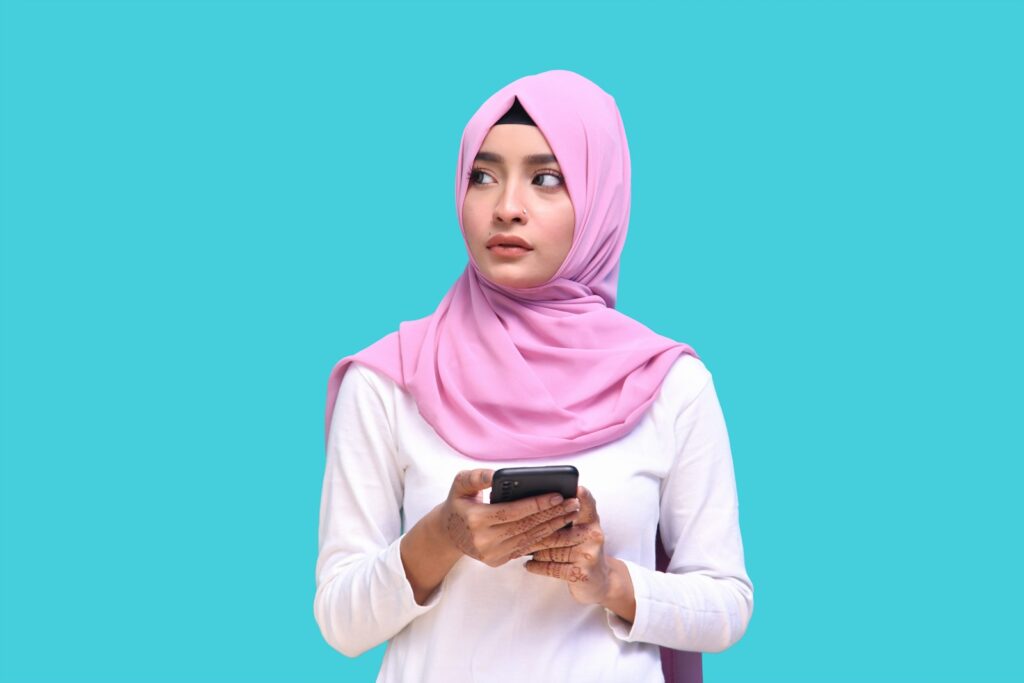 a person wearing a pink head scarf and holding a phone