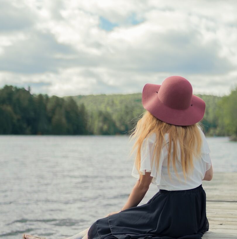 woman sitting on dock under cumulus clouds