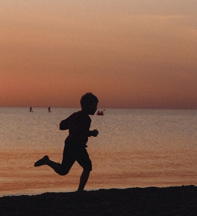 a person running on a beach at sunset