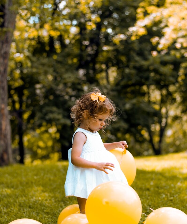 girl wearing white sleeveless dress beside balloons