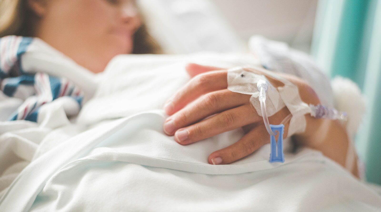 a woman laying in a hospital bed with an iv in her hand