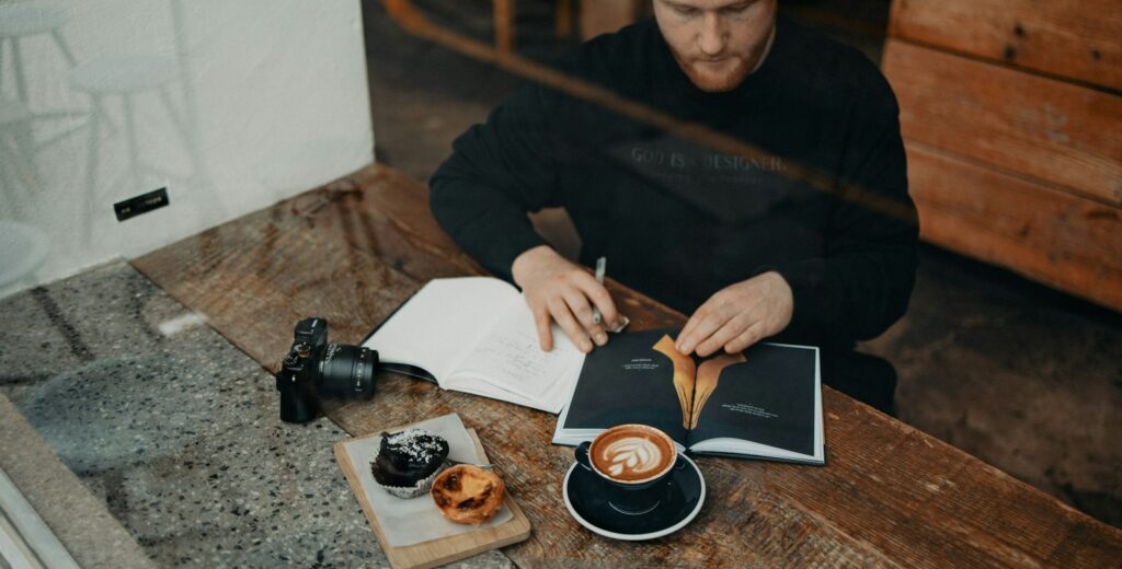a man sitting at a table with a book and a cup of coffee