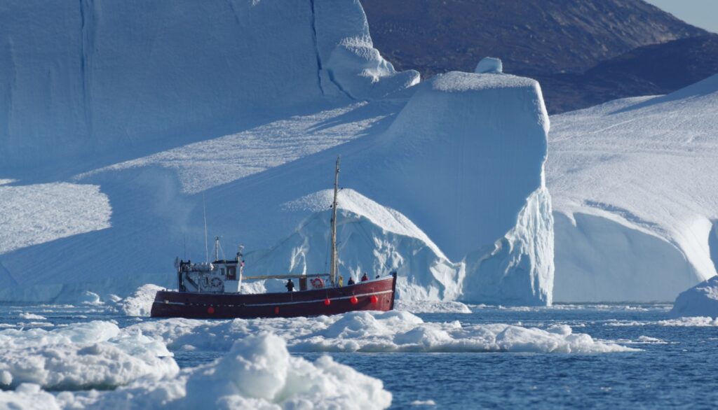 a boat in a body of water with icebergs in the background