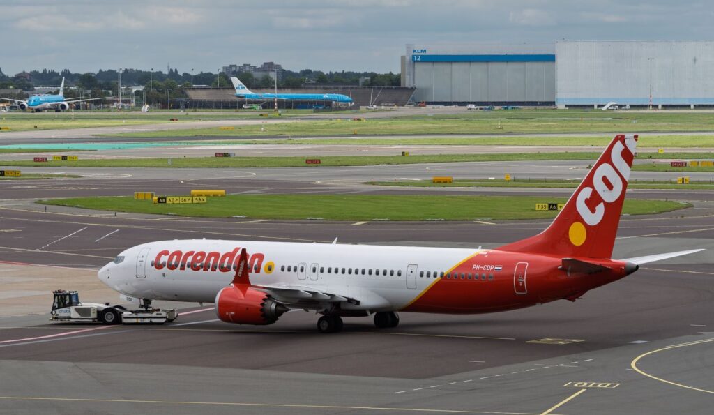 Corendon Airlines plane being towed at a busy airport with another aircraft in the background.